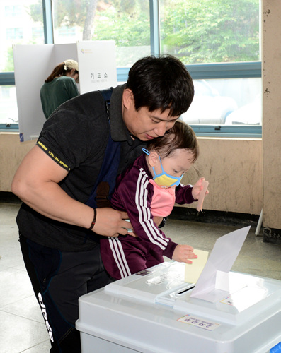 아빠와 함께 투표를 하고있는 어린이.