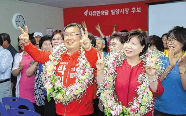 박일호 한국당 밀양시장 당선자가 14일 새벽 축하 꽃다발을 목에 걸고  인사하고 있다.