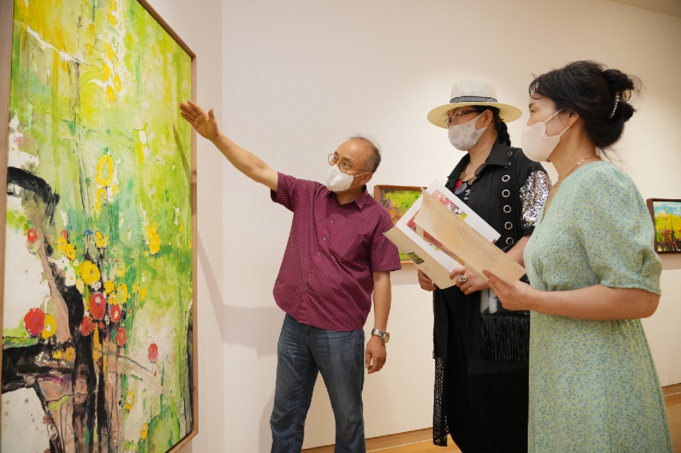강해중 작가(왼쪽 첫번째)가 BNK경남은행갤러리를 찾은 지역민들에게 작품을 안내하고 있다. BNK경남은행갤러리 제공
