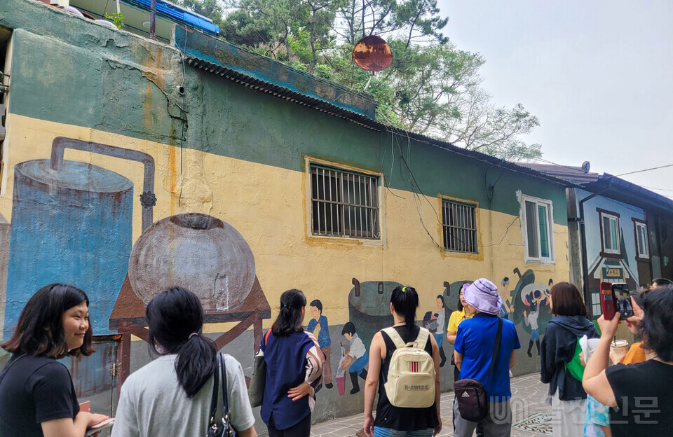 장생포 고래문화마을에서 참가자들이 한때 포경산업 전초기지였던 장생포 고래잡이 과정을 그린 벽화를 보고 있다.