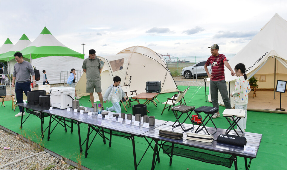 감성 캠핑 브랜드 '하드 기어(HARD GEAR)'의 텐트와 캠핑장비 전시를 둘러보고 있는 참가자들.