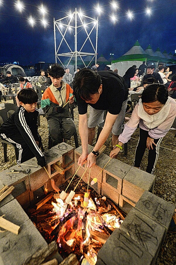 캠핑러 가족이 화로에 소시지와 마시멜로를 구워 먹고 있는 모습 (자료사진). 울산신문