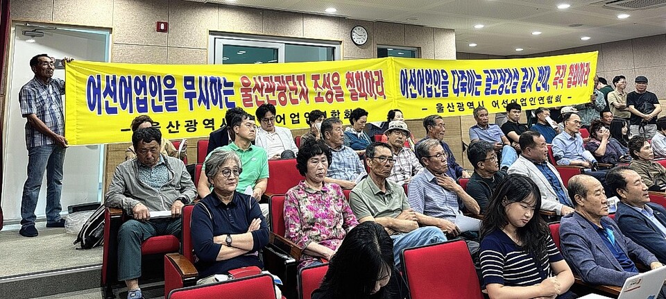 18일 울산 북구 강동문화센터에서 열린 '웨일즈코브 울산 관광단지' 환경영향평가 주민설명회에서 울산시 어선어업인연합회 회원들이 사업추진에 반대하는 내용의 현수막을 펼치고 있다. 엄시윤 기자 usw4746@